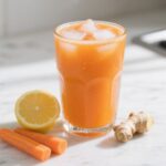 Final glass of Carrot Orange Ginger Juice with ice on marble