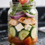 Fresh Greek Salad in a mason jar on black marble counter