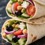 Greek Salad Wrap sliced open with fresh textures visible on black marble