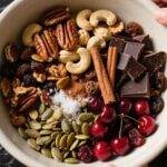 Homemade trail mix with nuts, seeds, and dried fruit on black marble countertop
