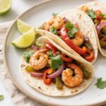 Shrimp fajitas served with peppers, onion, and cilantro in tortillas.