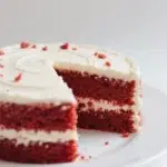 homemade red velvet cake with cream cheese frosting, sliced to show rich red layers and soft texture.