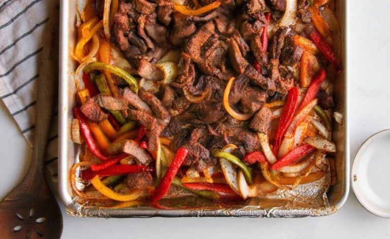 Whole30 sheet pan steak fajitas with peppers and lime on a foil tray.