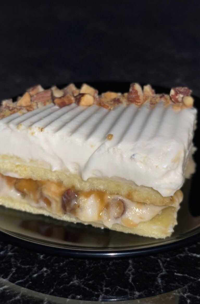 A close-up of a sliced Almond Caramel Layer Cake showcasing its golden sponge, caramel whipped cream, and toasted almonds.