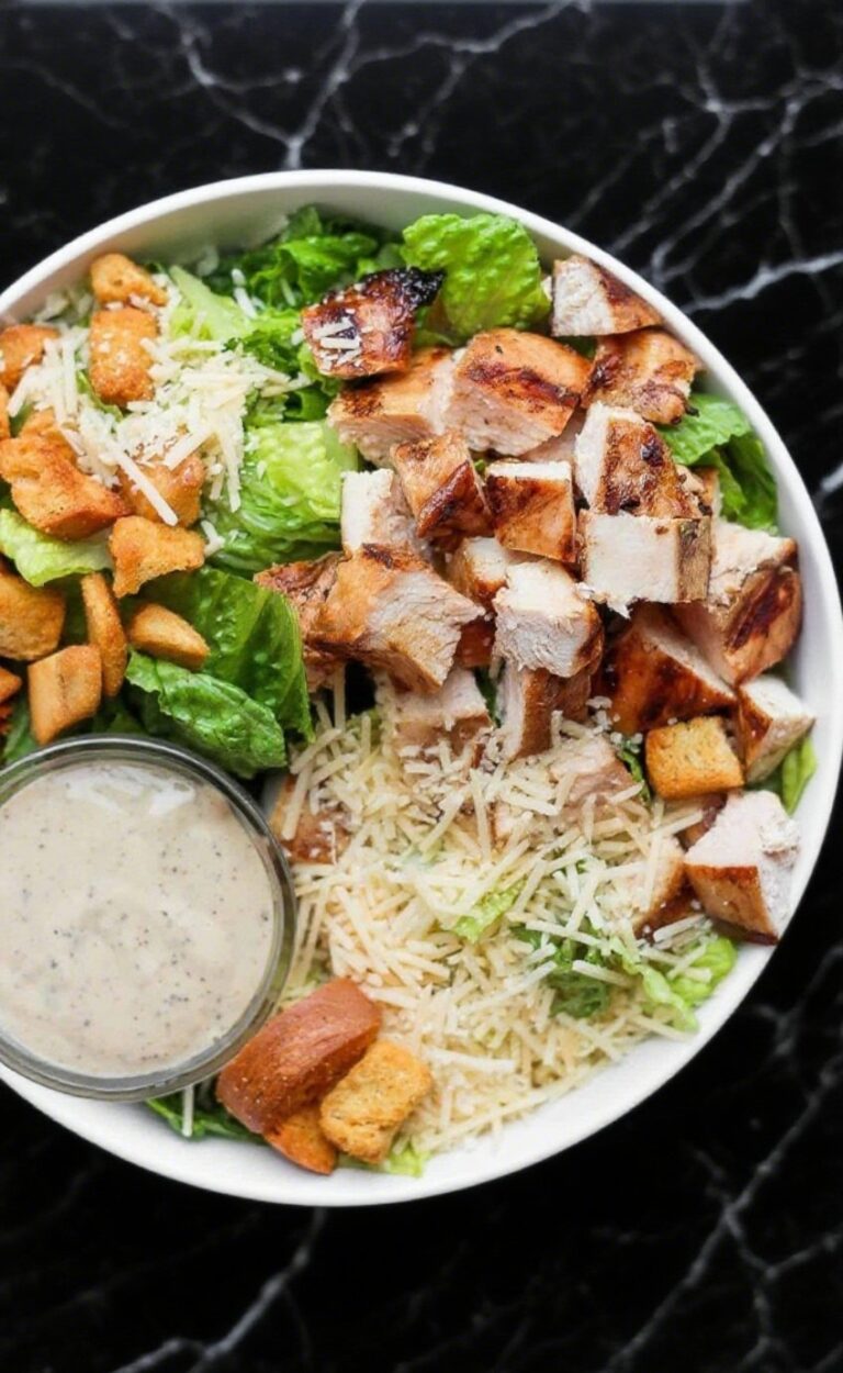 Grilled Chicken Caesar Salad with romaine lettuce, grilled chicken slices, croutons, parmesan, and Caesar dressing, served in a bowl.