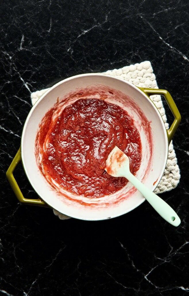 Maple Rhubarb Jam in a jar with rhubarb stalks in the background