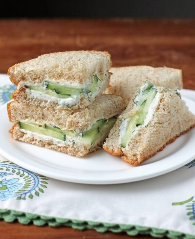 Cucumber sandwiches on a plate with garnish, served for tea.