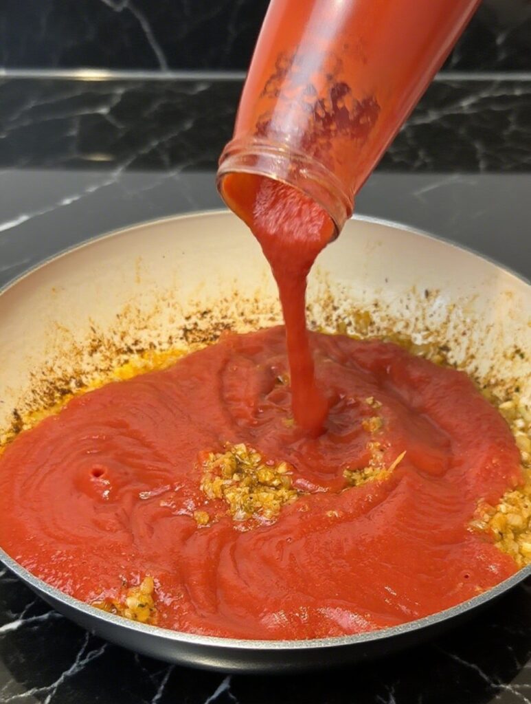 Close-up of creamy butter chicken sauce simmering in a skillet, showcasing its rich orange color and velvety texture