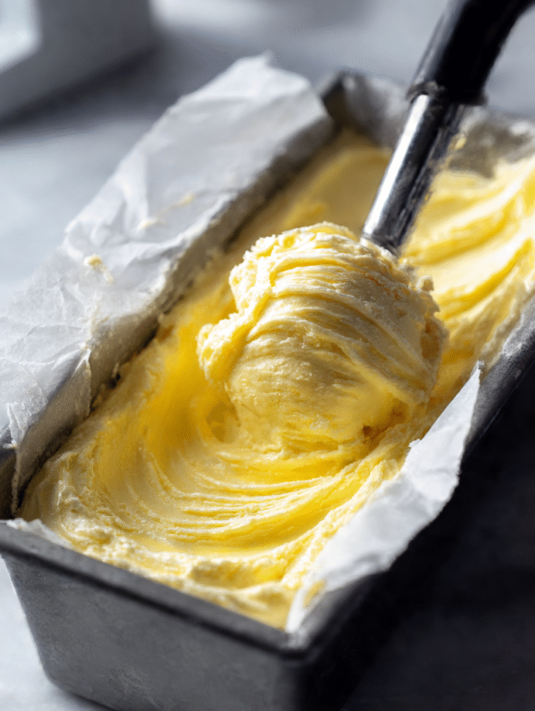 Transferring freshly churned Lemon Curd Ice Cream with swirls into a loaf pan.